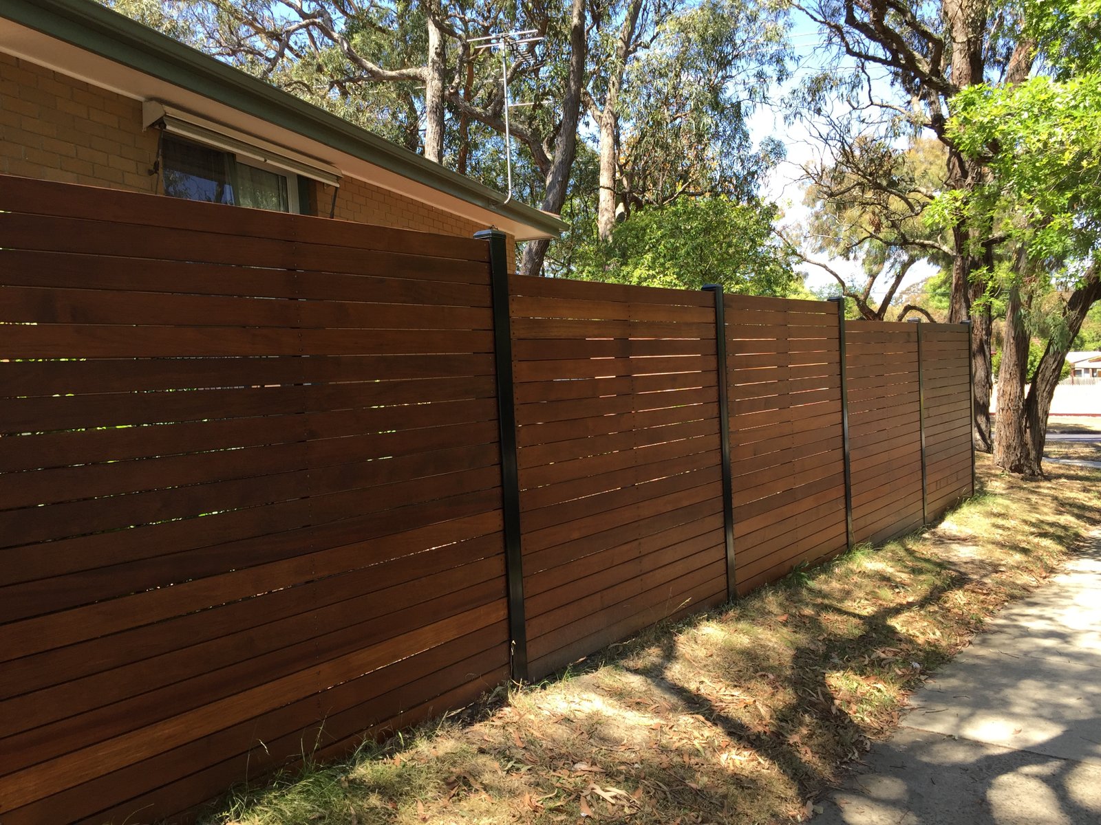 Horizontal hardwood slat fence with black steel posts